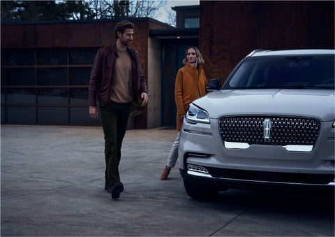 A man and a woman approaching a 2023 Lincoln Aviator® SUV, which illuminates certain lights when they are close | Kirk Brothers Lincoln of Vicksburg in Vicksburg MS