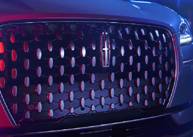 The grille of a 2025 Lincoln Corsair® SUV reflects neon light at night. | Kirk Brothers Lincoln of Vicksburg in Vicksburg MS