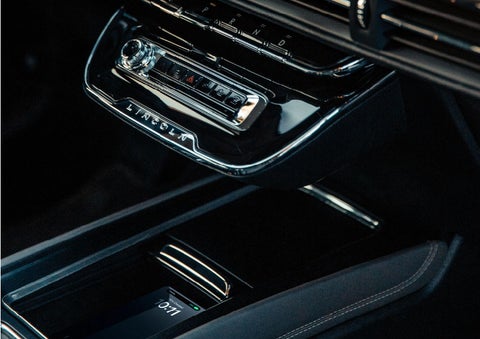 A smartphone is is being placed on the wireless charging pad in the front center console cubby. | Kirk Brothers Lincoln of Vicksburg in Vicksburg MS